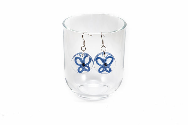 Okrogli viseči uhani iz epoksidne smole s čipkastim metuljem v različnih barvah. Na kaveljčkih iz nerjavečega jekla.