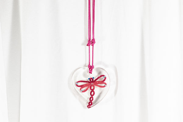 Temno rdeč kačji pastir iz čipke in perl v obesku iz epoksidene smole srčaste oblike. Visi na povoščeni bombažni vrvici.