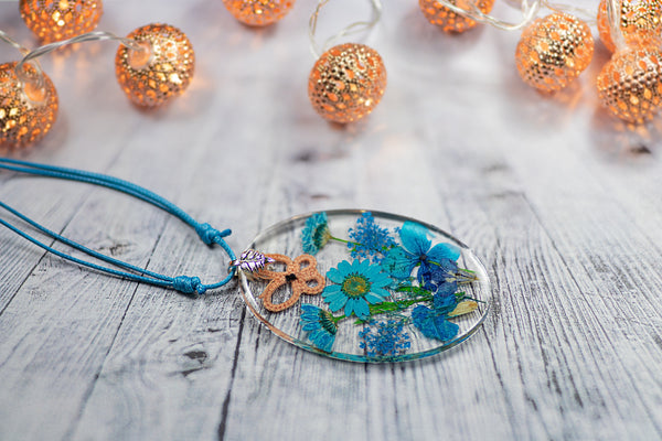 OVAL TURQUOISE PENDANT WITH AN APRICOT BUTTERFLY ON BLUE FLOWERS