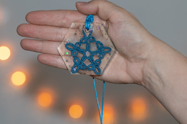 Šestkoten obesek iz epoksidne smole na daljši modri vrvici iz povoščenega bombaža. Z modro zvezdo iz čipke in nekaj bleščicami.