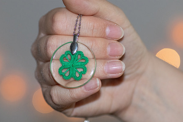 Manjši okrogel obesek iz epoksidne smole, s čipko v obliki štiriperesne detelje, na izbiro v dveh odtenkih zelene.