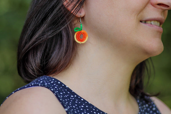 Čipkasti viseči uhani v obliki rumeno oranžne pomaranče, ki visijo na kaveljčkih iz nerjavečega jekla.