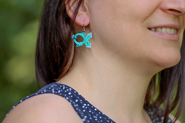 Čipkasti viseči uhani v obliki ribe s perlami v pestri paleti barv, ki visijo na kaveljčkih iz nerjavečega jekla.