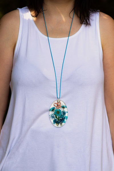 OVAL TURQUOISE PENDANT WITH AN APRICOT BUTTERFLY ON BLUE FLOWERS