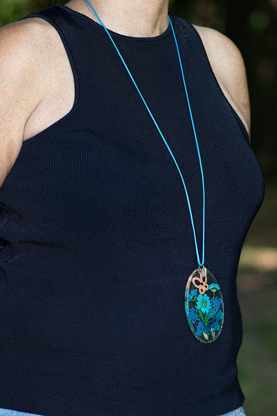 OVAL TURQUOISE PENDANT WITH AN APRICOT BUTTERFLY ON BLUE FLOWERS
